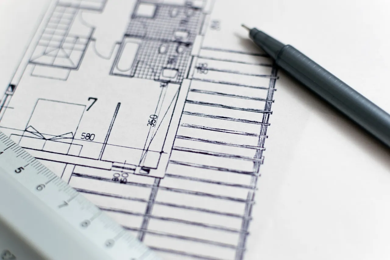 Construction plans and building permit documents laid out on a desk for a Minnesota deck project