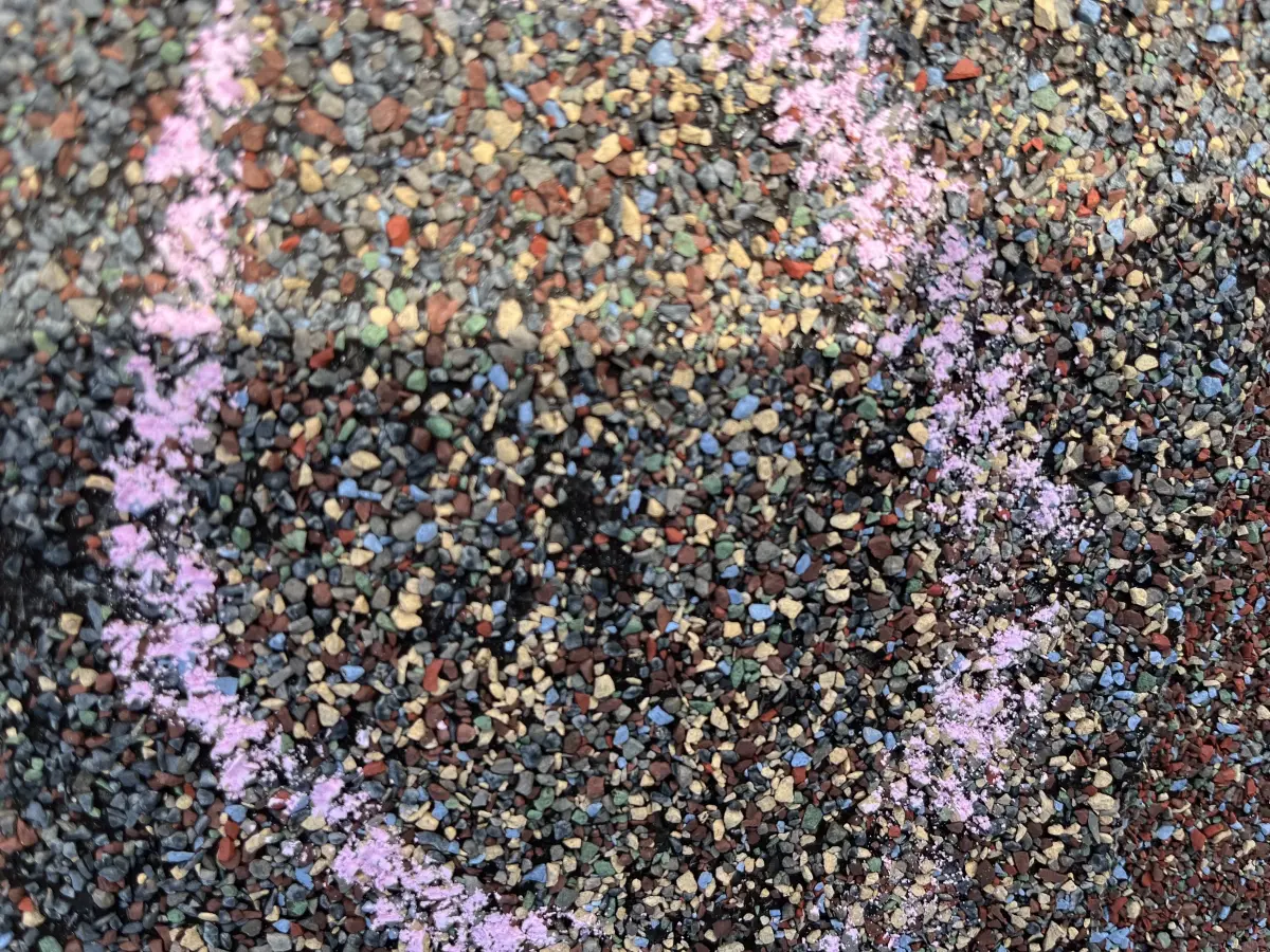 Chalk-marked hail impact spots on roof shingles showing granule loss during an insurance adjuster inspection