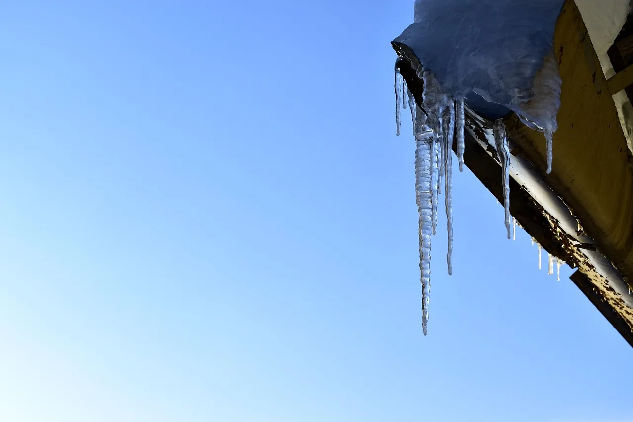 Heated gutter system with heat cables installed along roof edge and gutters preventing ice dam formation