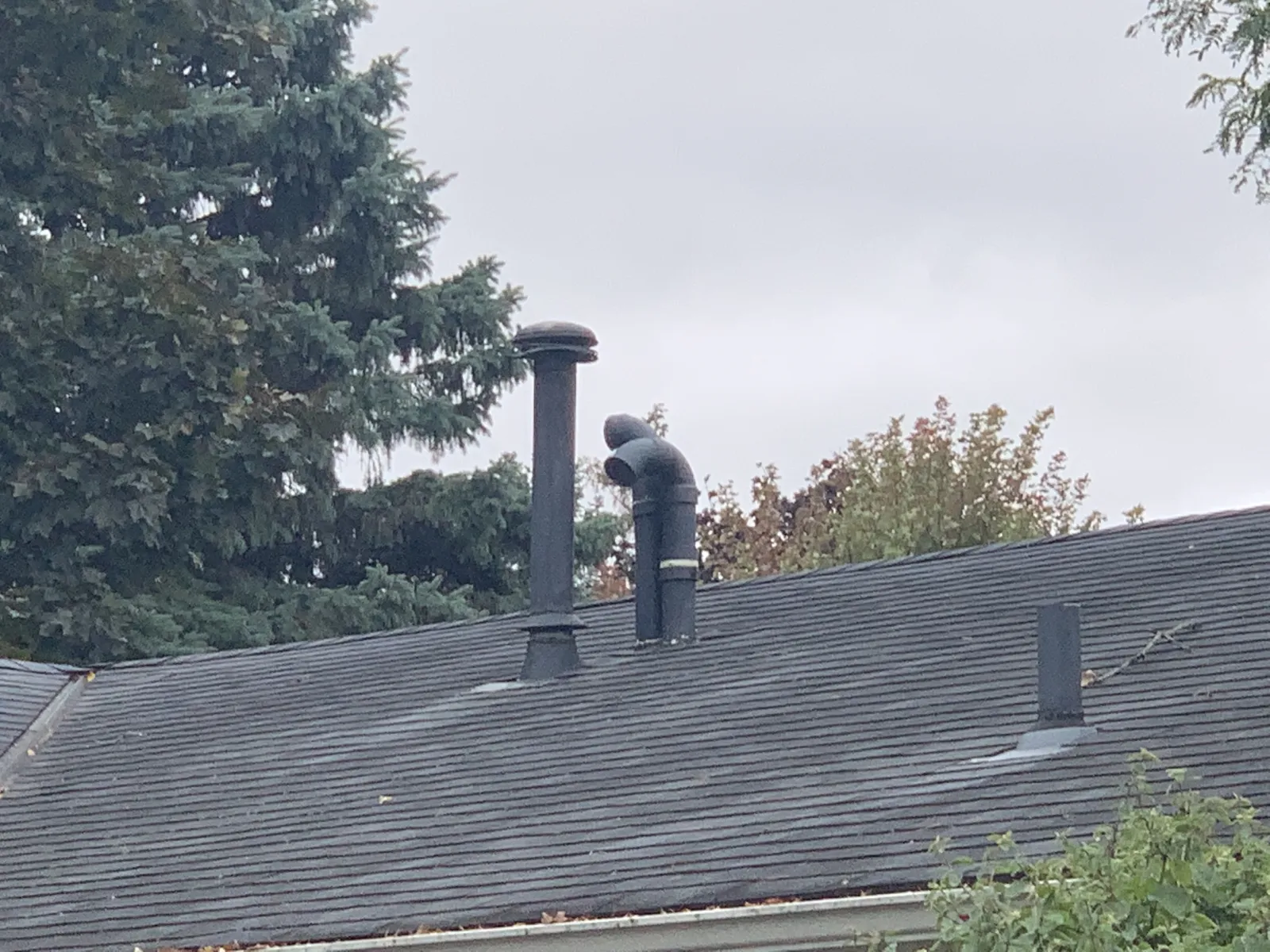 Storm-damaged roof showing bent vent pipes and deteriorated shingles needing emergency roof repair