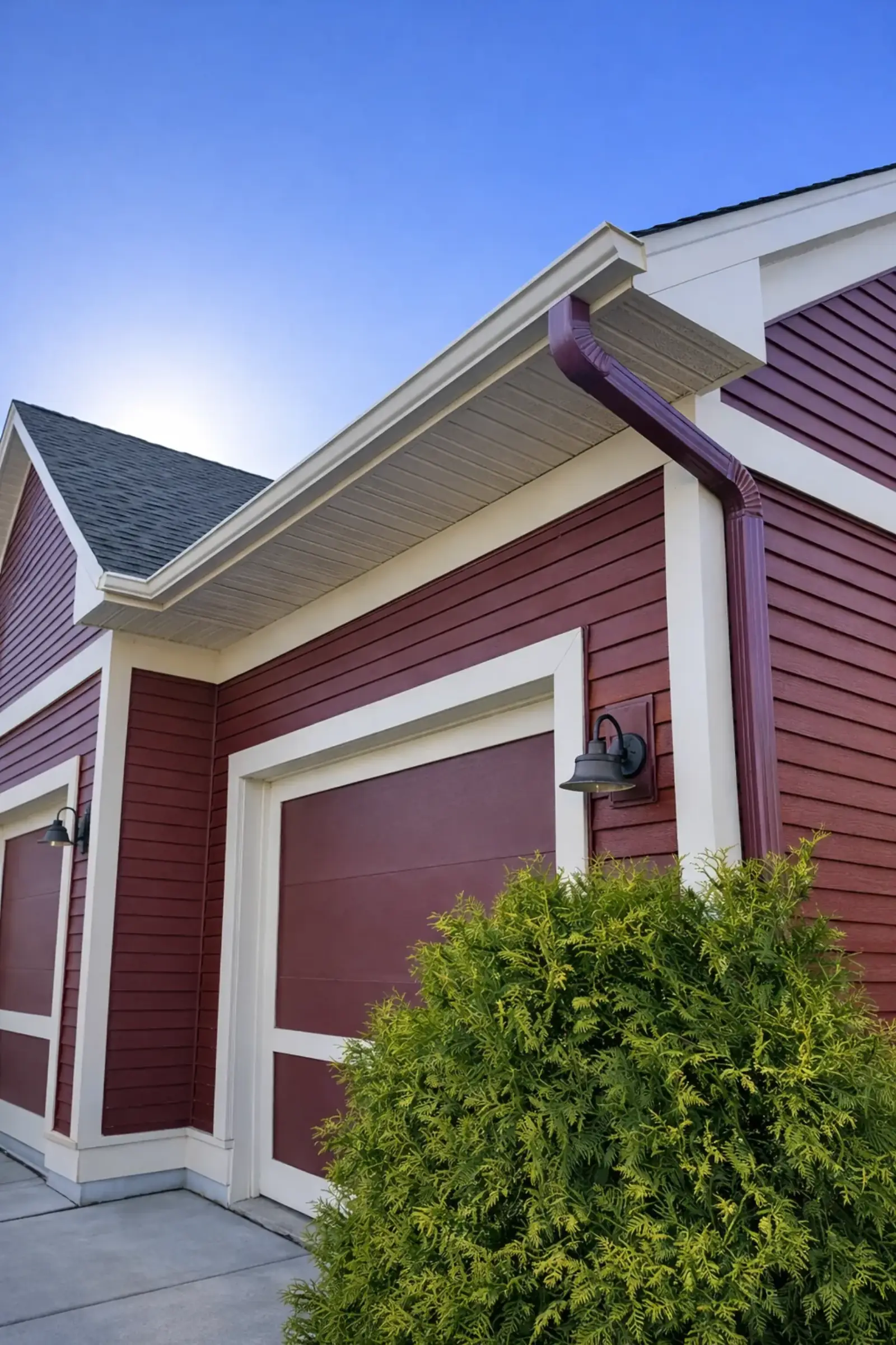 Completed siding and gutter installation with red lap siding and white trim